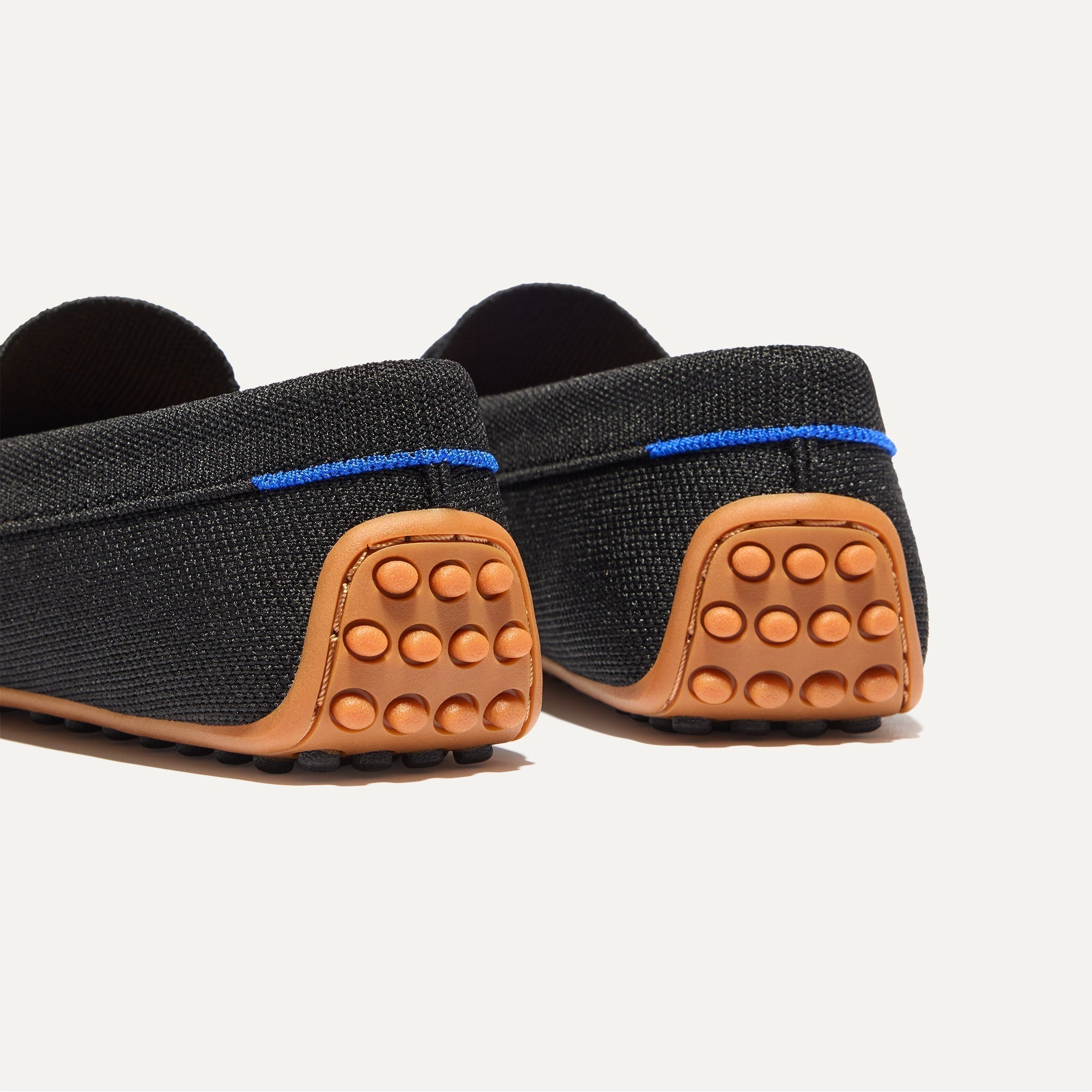 Close up of the heel of The Daily Driver in Black, with raised peg outsoles and Rothy's signature blue halo. 