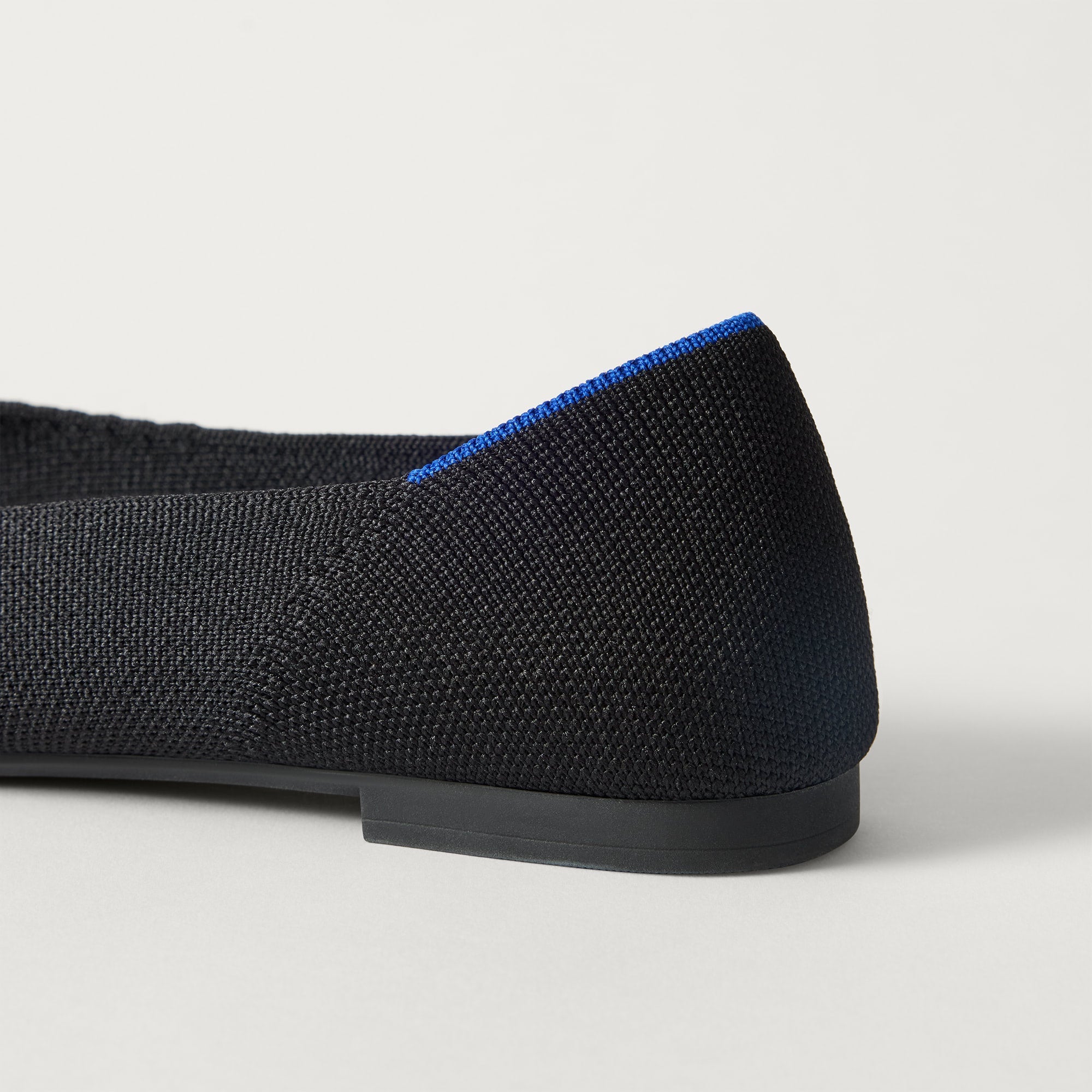 Close up of the heel of The Point III in Black, with Rothy's signature blue halo. 