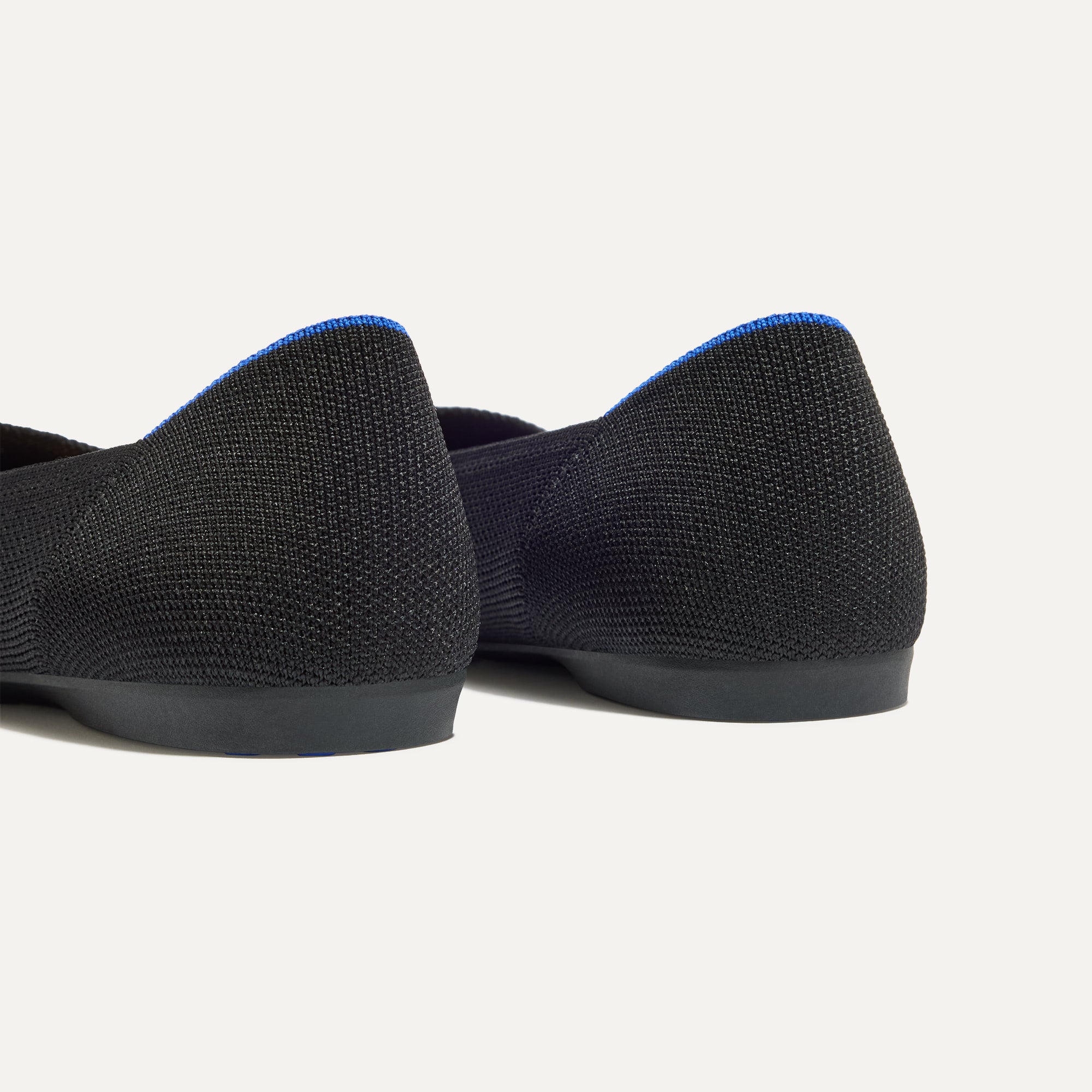 Close up of the heel of The Daily Flat in Black, with Rothy's signature blue halo. 